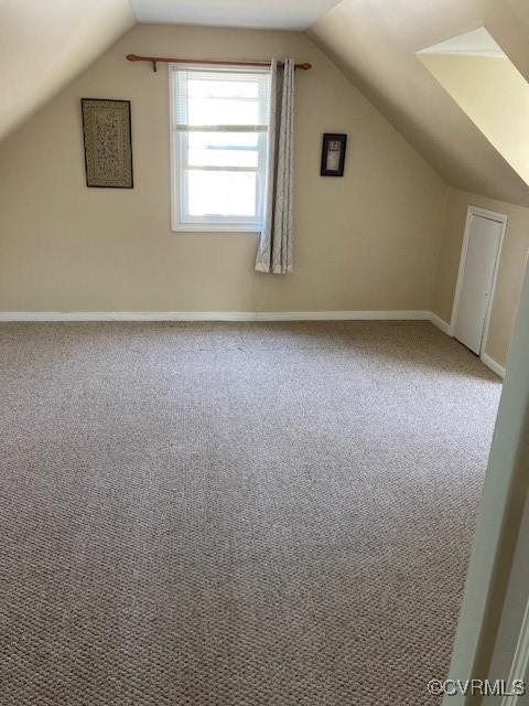 additional living space with vaulted ceiling, carpet floors, and baseboards