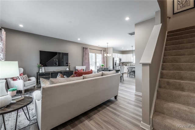 living area featuring light wood-style flooring, recessed lighting, visible vents, stairway, and an inviting chandelier