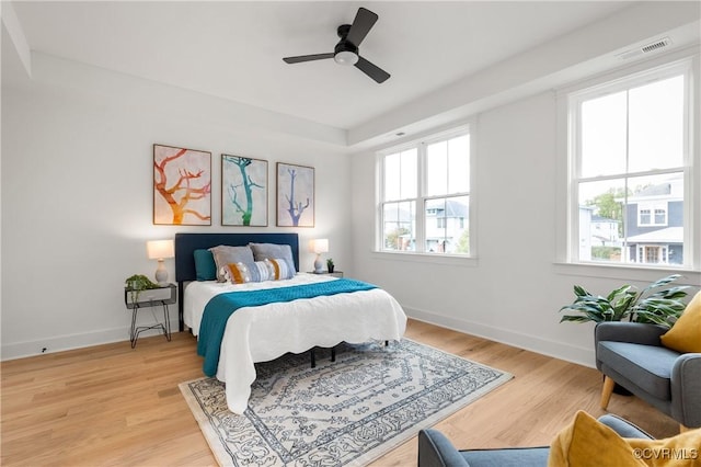 bedroom with baseboards, ceiling fan, visible vents, and light wood finished floors