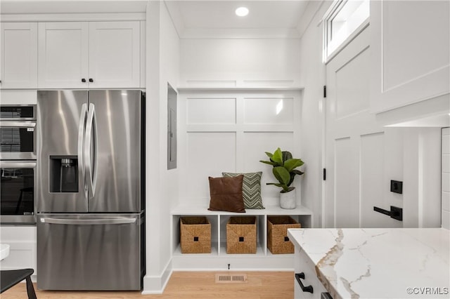 kitchen featuring light stone counters, light wood-style flooring, a decorative wall, visible vents, and appliances with stainless steel finishes