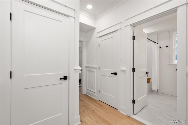 corridor with marble finish floor and crown molding