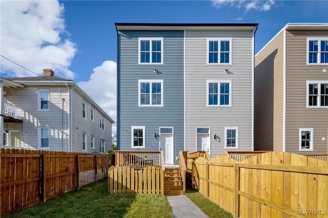 rear view of property featuring a fenced backyard, a lawn, and a deck