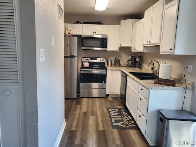 kitchen with a sink, stainless steel appliances, dark wood-style floors, and white cabinetry