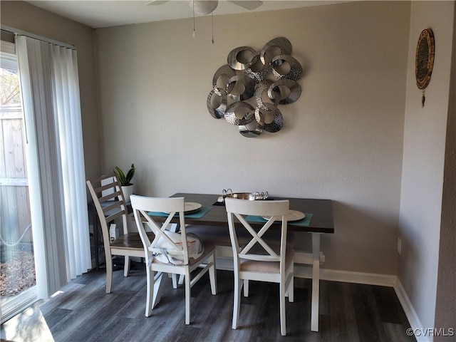 dining space featuring ceiling fan with notable chandelier, wood finished floors, and baseboards