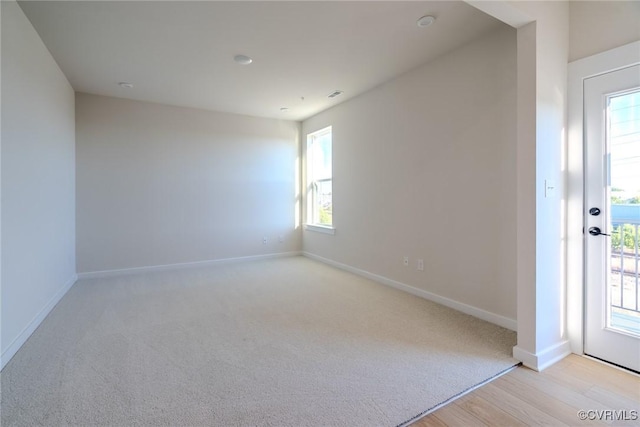 unfurnished room featuring light colored carpet, visible vents, and baseboards