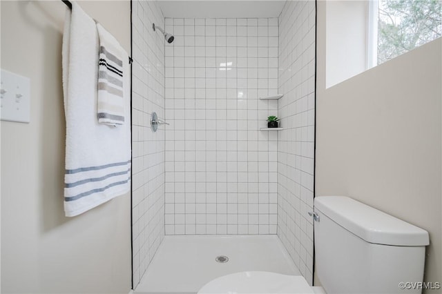 bathroom with toilet and a tile shower