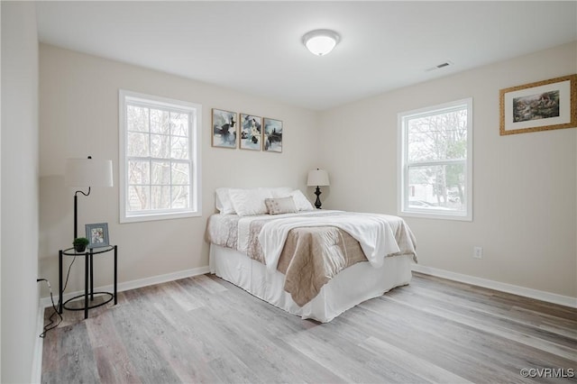 bedroom featuring baseboards, visible vents, and wood finished floors