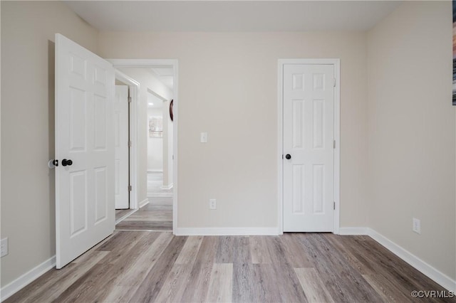 unfurnished bedroom featuring wood finished floors and baseboards