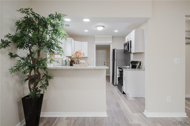 kitchen featuring baseboards, appliances with stainless steel finishes, light stone counters, a peninsula, and white cabinetry