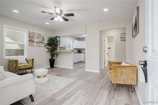 living area with baseboards, recessed lighting, a wealth of natural light, and light wood-style floors