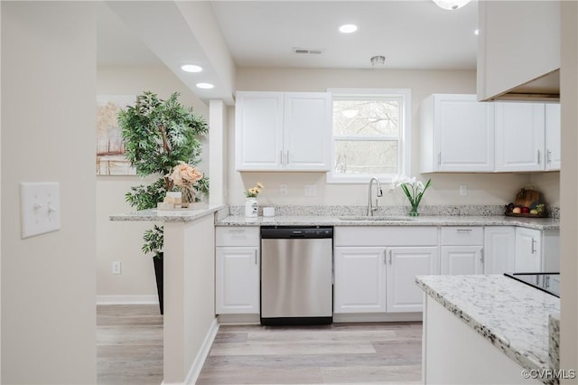 kitchen featuring stainless steel dishwasher, a sink, light stone counters, and white cabinets