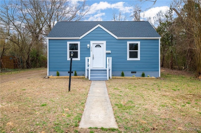 bungalow-style house with crawl space, roof with shingles, and a front lawn