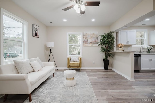 living area featuring light wood finished floors, visible vents, baseboards, a ceiling fan, and recessed lighting