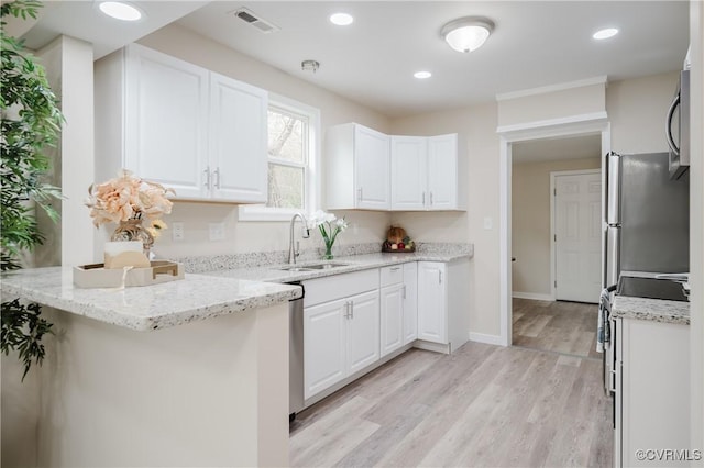 kitchen with visible vents, light wood-style flooring, appliances with stainless steel finishes, white cabinetry, and a sink