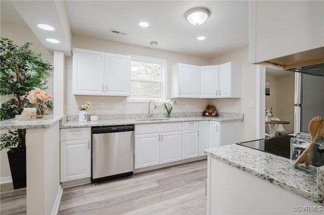 kitchen with light wood-type flooring, appliances with stainless steel finishes, white cabinets, and a sink