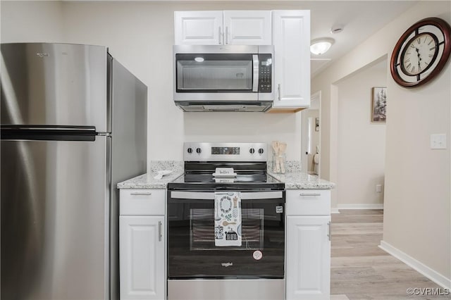 kitchen with stainless steel appliances, light stone counters, and white cabinets