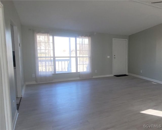 spare room with baseboards and wood finished floors