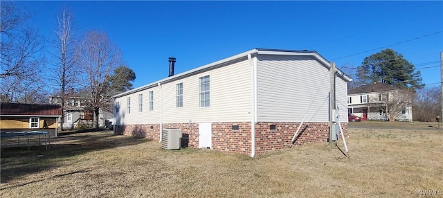 view of property exterior featuring central air condition unit, a trampoline, and a lawn