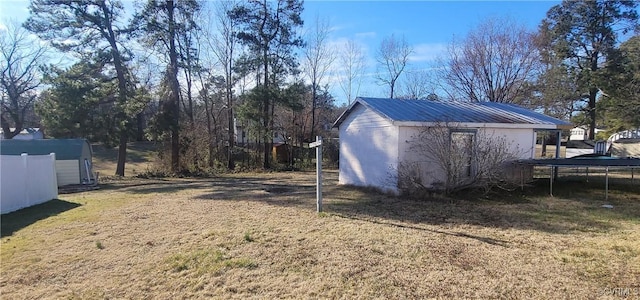 view of yard featuring an outbuilding, a storage shed, and a trampoline