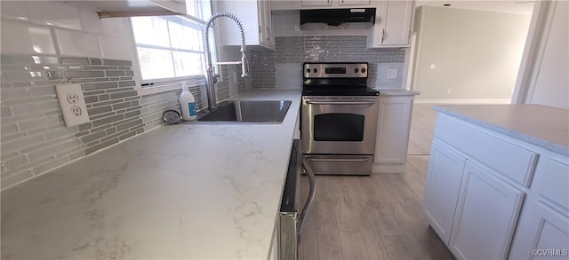 kitchen featuring stainless steel electric stove, decorative backsplash, white cabinets, a sink, and ventilation hood