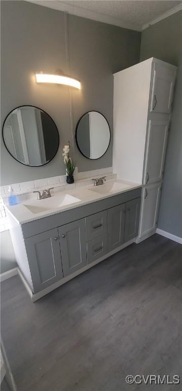 full bathroom featuring a textured ceiling, double vanity, wood finished floors, and a sink