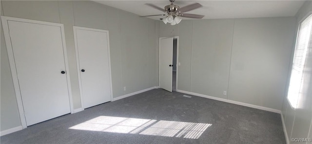 unfurnished bedroom with ceiling fan and dark colored carpet