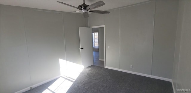 unfurnished room featuring a ceiling fan, dark colored carpet, and a decorative wall