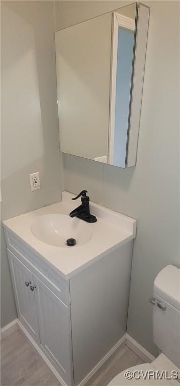 bathroom with toilet, baseboards, wood finished floors, and vanity