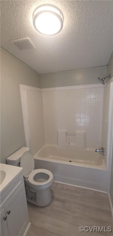 bathroom featuring toilet, shower / bathing tub combination, a textured ceiling, and visible vents