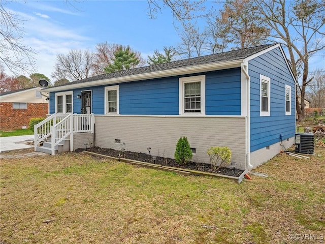 view of front of home with a front lawn, crawl space, a shingled roof, and cooling unit