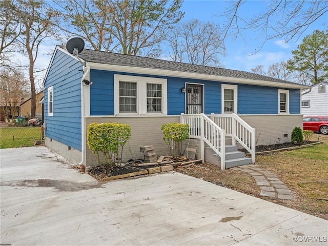 view of front of house featuring a shingled roof, crawl space, and fence