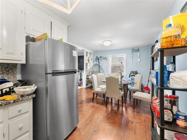 kitchen featuring tasteful backsplash, freestanding refrigerator, white cabinetry, and wood finished floors