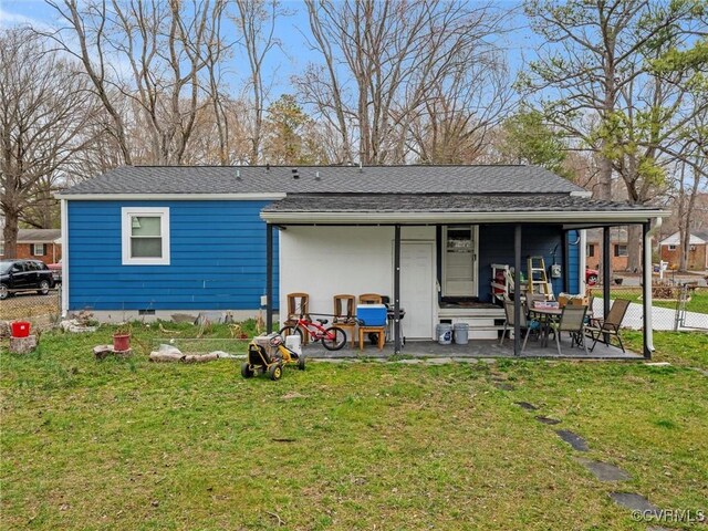 back of property featuring a shingled roof, crawl space, a lawn, and a patio