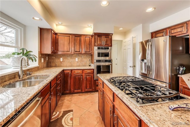 kitchen with light stone counters, recessed lighting, backsplash, appliances with stainless steel finishes, and a sink