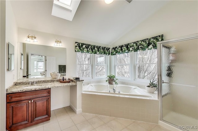 full bathroom featuring a stall shower, vaulted ceiling with skylight, a garden tub, tile patterned flooring, and vanity