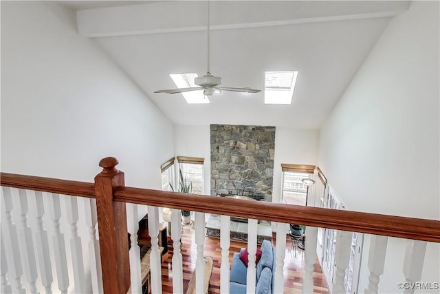 staircase featuring lofted ceiling with skylight, a ceiling fan, and a stone fireplace