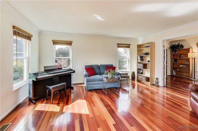 sitting room with baseboards, wood-type flooring, visible vents, and crown molding