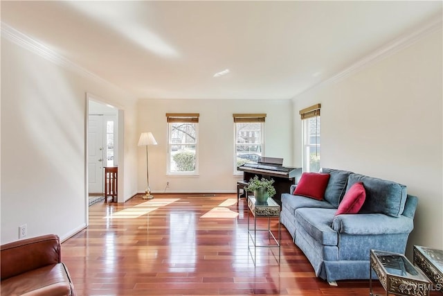 living area with crown molding, baseboards, wood finished floors, and a healthy amount of sunlight