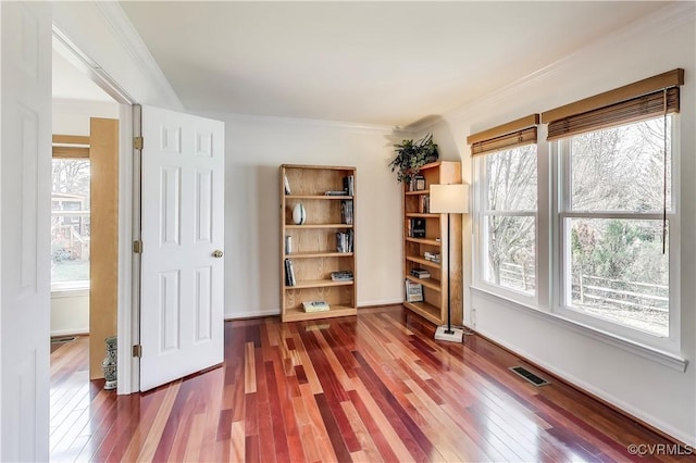 interior space featuring crown molding, wood-type flooring, visible vents, and a healthy amount of sunlight