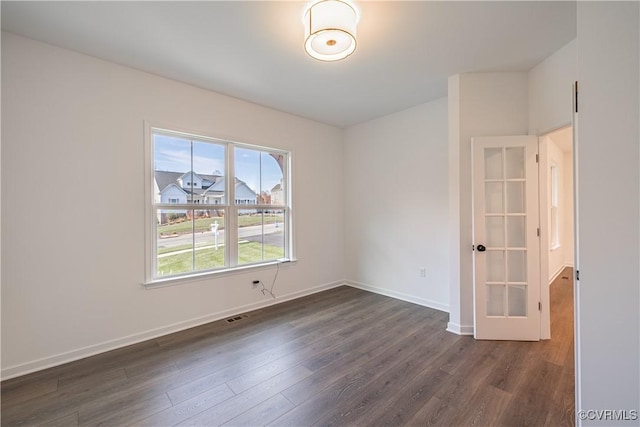 spare room with visible vents, baseboards, and dark wood-style flooring