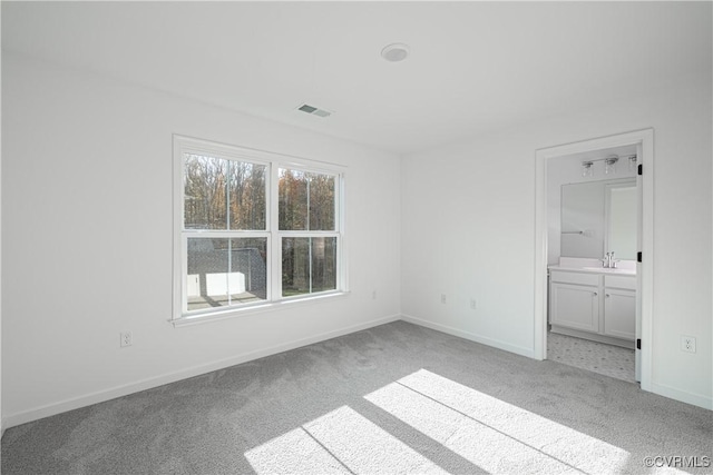 unfurnished bedroom featuring baseboards, visible vents, a sink, and light colored carpet