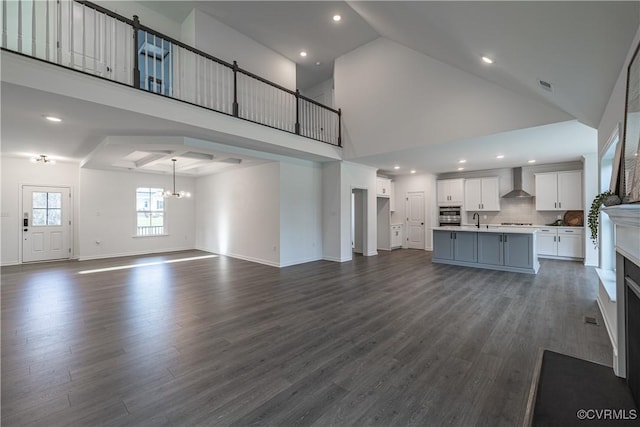 unfurnished living room featuring high vaulted ceiling, dark wood-style flooring, a sink, visible vents, and baseboards