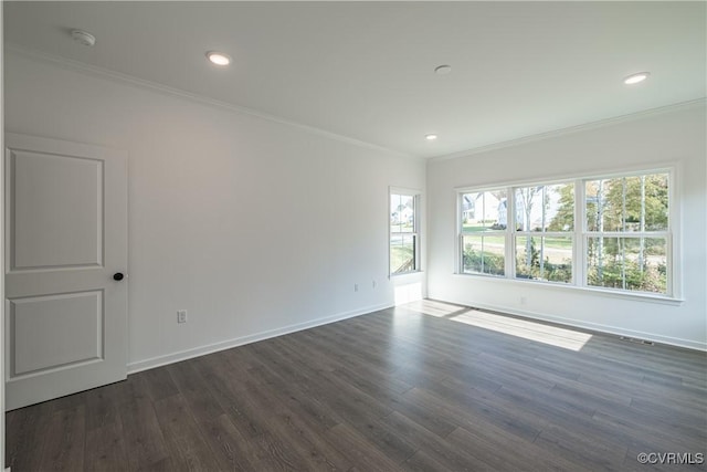 spare room featuring dark wood-style floors, crown molding, and baseboards