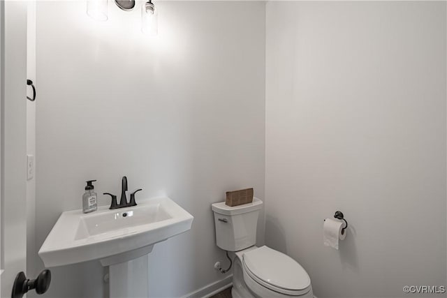 bathroom with toilet, baseboards, and a sink