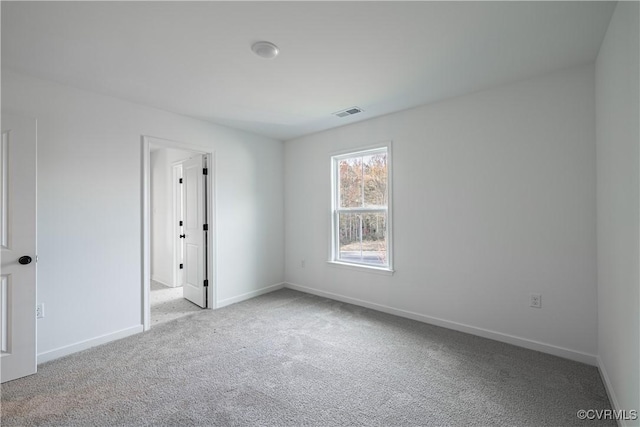 carpeted spare room with visible vents and baseboards