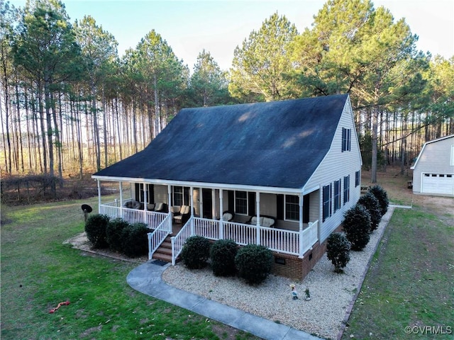 view of front of home featuring an outbuilding, a porch, a front lawn, and a shingled roof