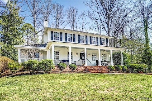 view of front of home featuring a porch, a chimney, a front yard, and a ceiling fan