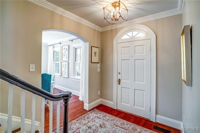 entrance foyer with stairway, dark wood-style floors, arched walkways, and a wealth of natural light