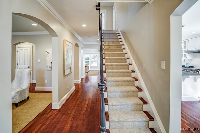 staircase featuring recessed lighting, crown molding, baseboards, and wood finished floors