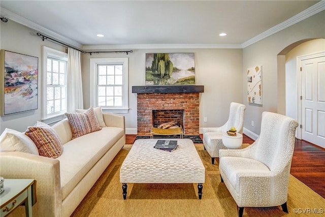 living area with wood finished floors, arched walkways, a fireplace, crown molding, and baseboards